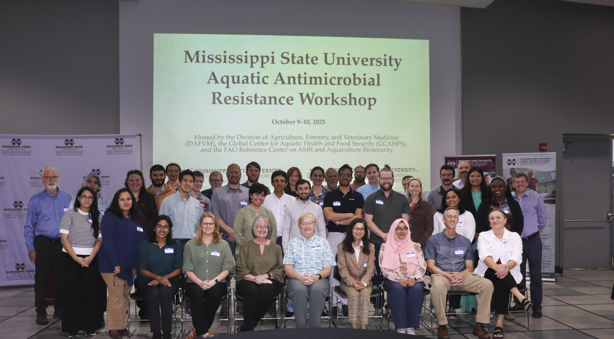 AMR workshop participants pose as a group in front of a screen displaying the workshop name